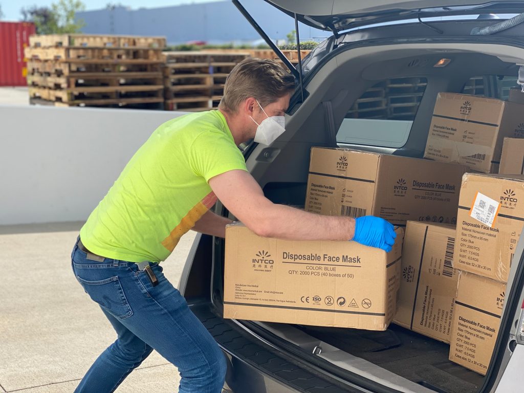 man loading boxes of face masks into car