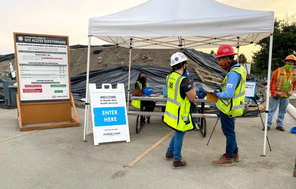 construction workers standing outside a mobile-med tent