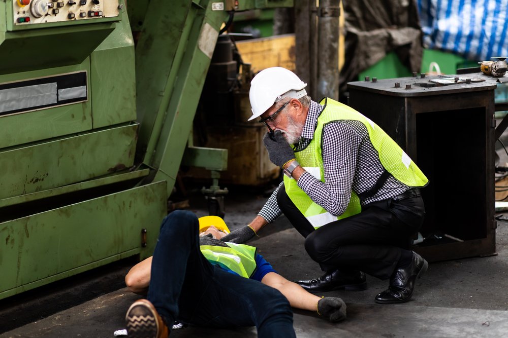 worker on floor with other worker providing first aid assistance