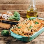 casserole-with-pasta-mushrooms-broccoli-sauce-cheese-rustic-wooden-background_259258-626