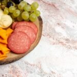 front-view-different-snacks-cips-sausages-cheese-fresh-grapes-light-white-space_140725-79345