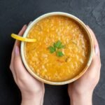 top-view-delicious-lentil-soup-with-female-holding-plate-dark-bread-loafs-dark-surface_179666-35086